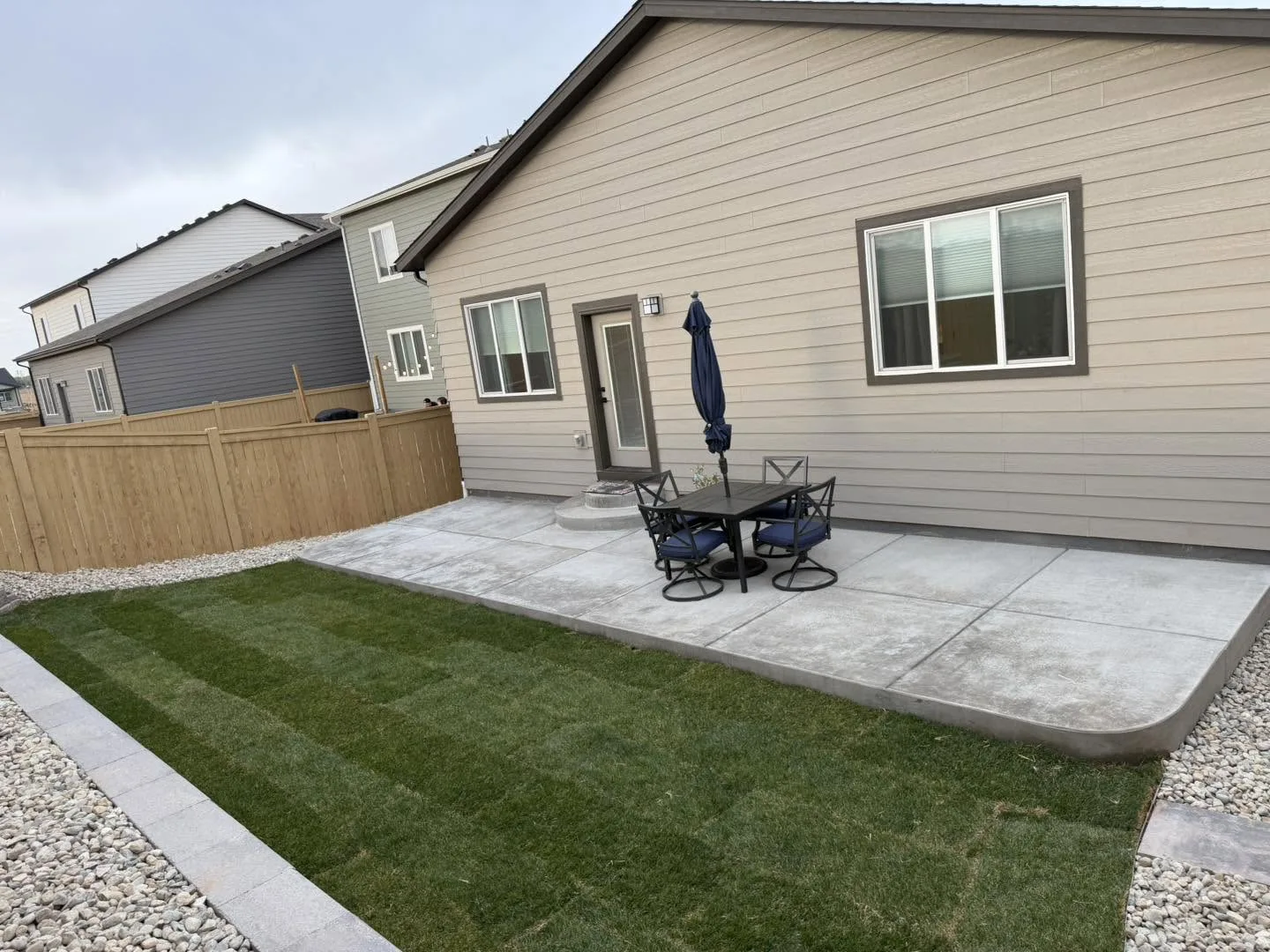The same backyard after — fresh green sod, a stamped concrete patio and clean paver borders by SOL Creations