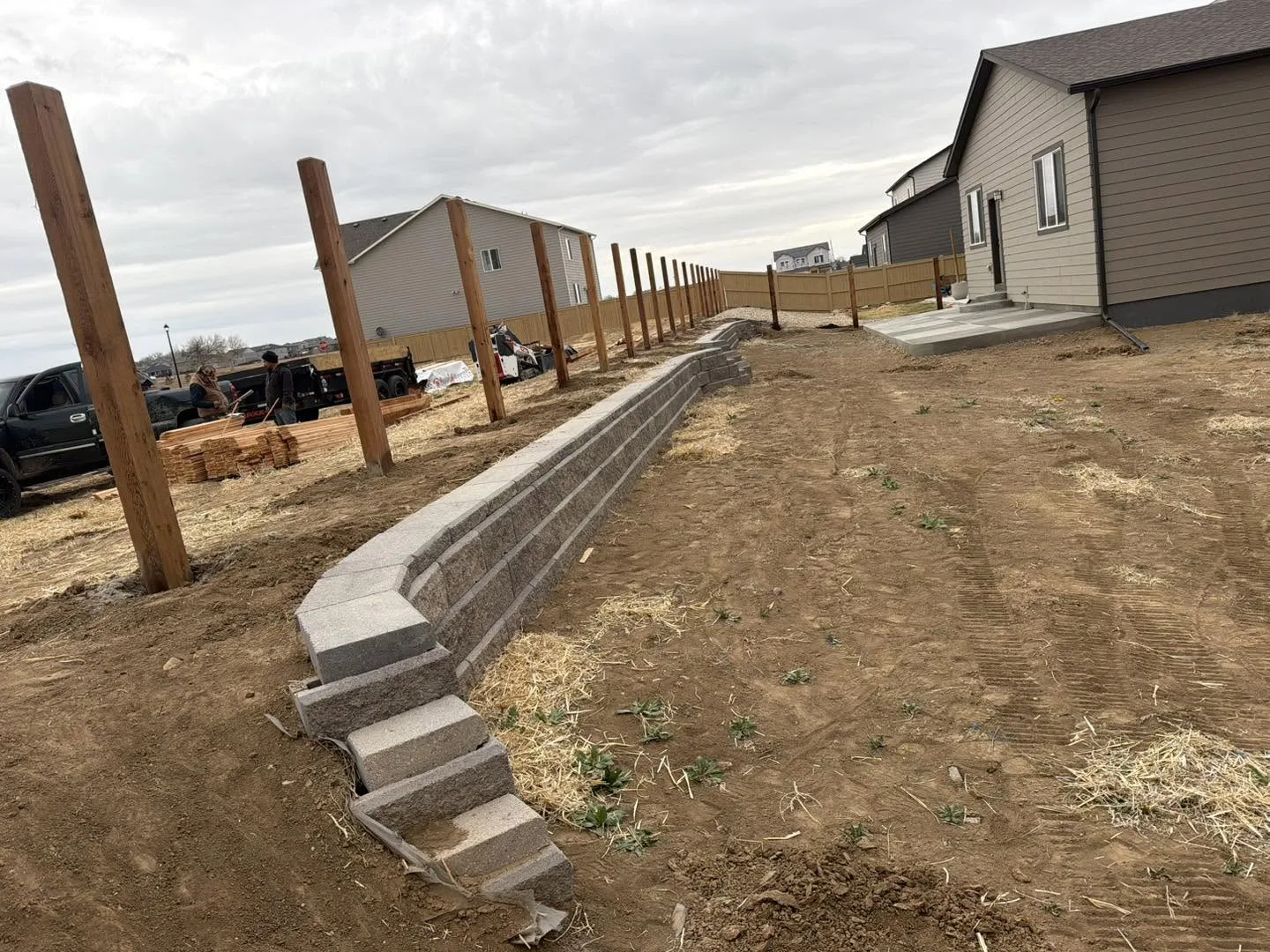 A bare dirt backyard with a new retaining wall going in, before SOL Creations finished it